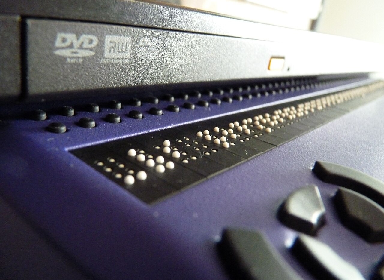 A laptop computer with a refreshable braille display attached, representing assistive technology used to access web content